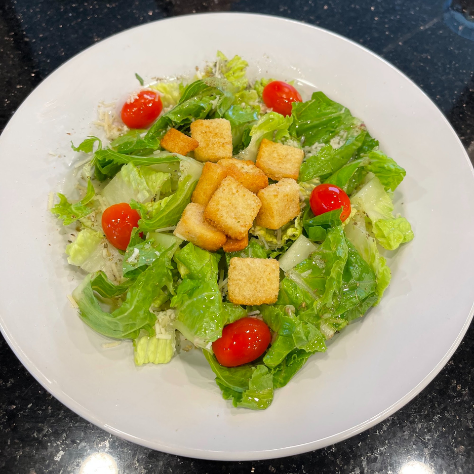 Fresh Caesar salad with crisp romaine, cherry tomatoes, croutons, and grated Parmesan cheese.